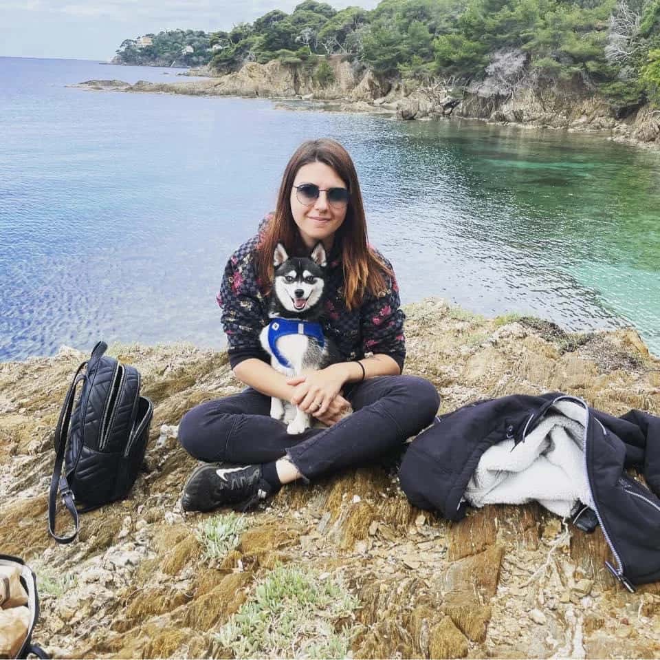 Aurélie avec un Pomsky assis au bord d'un lac